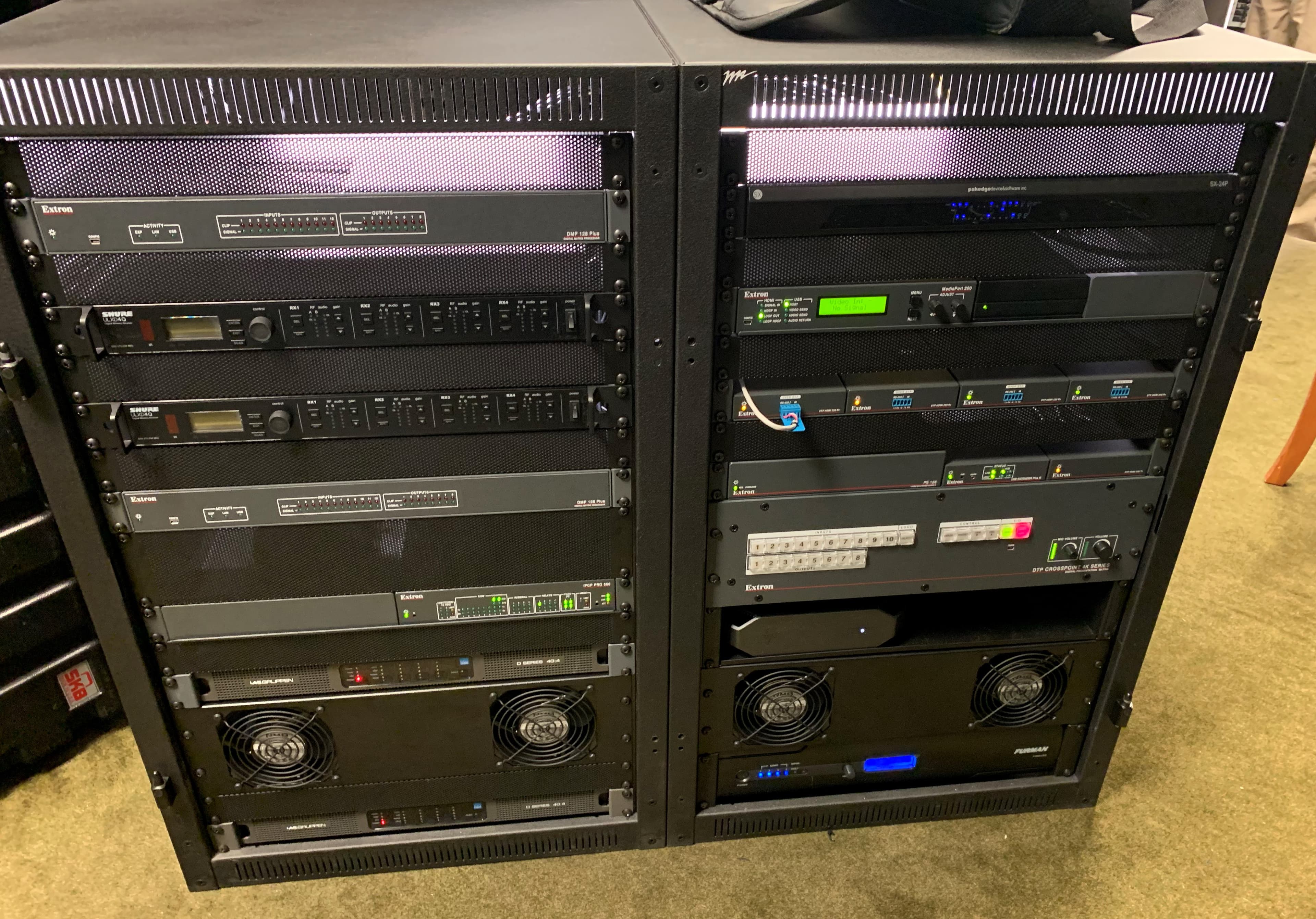Professional AV equipment rack with Extron, QSC, and other branded rackmount hardware