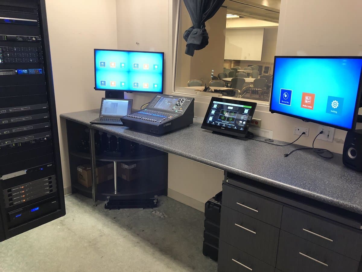 AV control room with mixing console, touchscreen, and multi-display monitoring