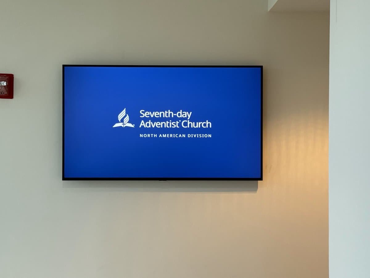 Wall-mounted digital signage display showing SDA North American Division branding